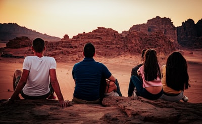 白天坐在棕色岩石上的男人和女人
